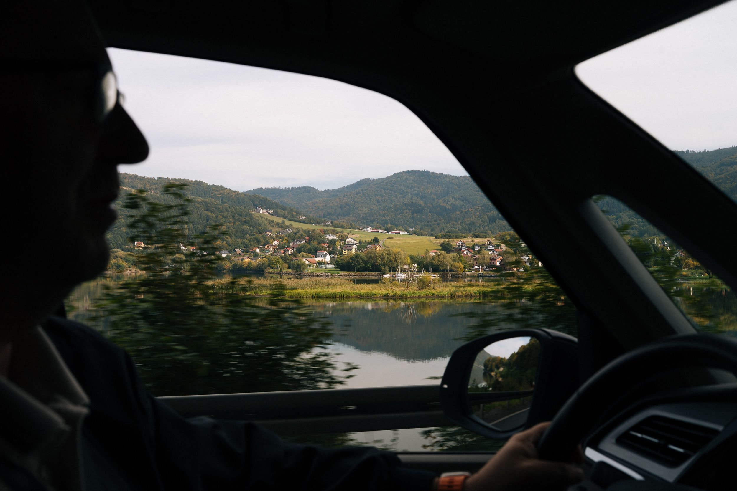 Silhouette des Fahrers in der Kabine, hinter der Scheibe der Żywiecer See und die Berge