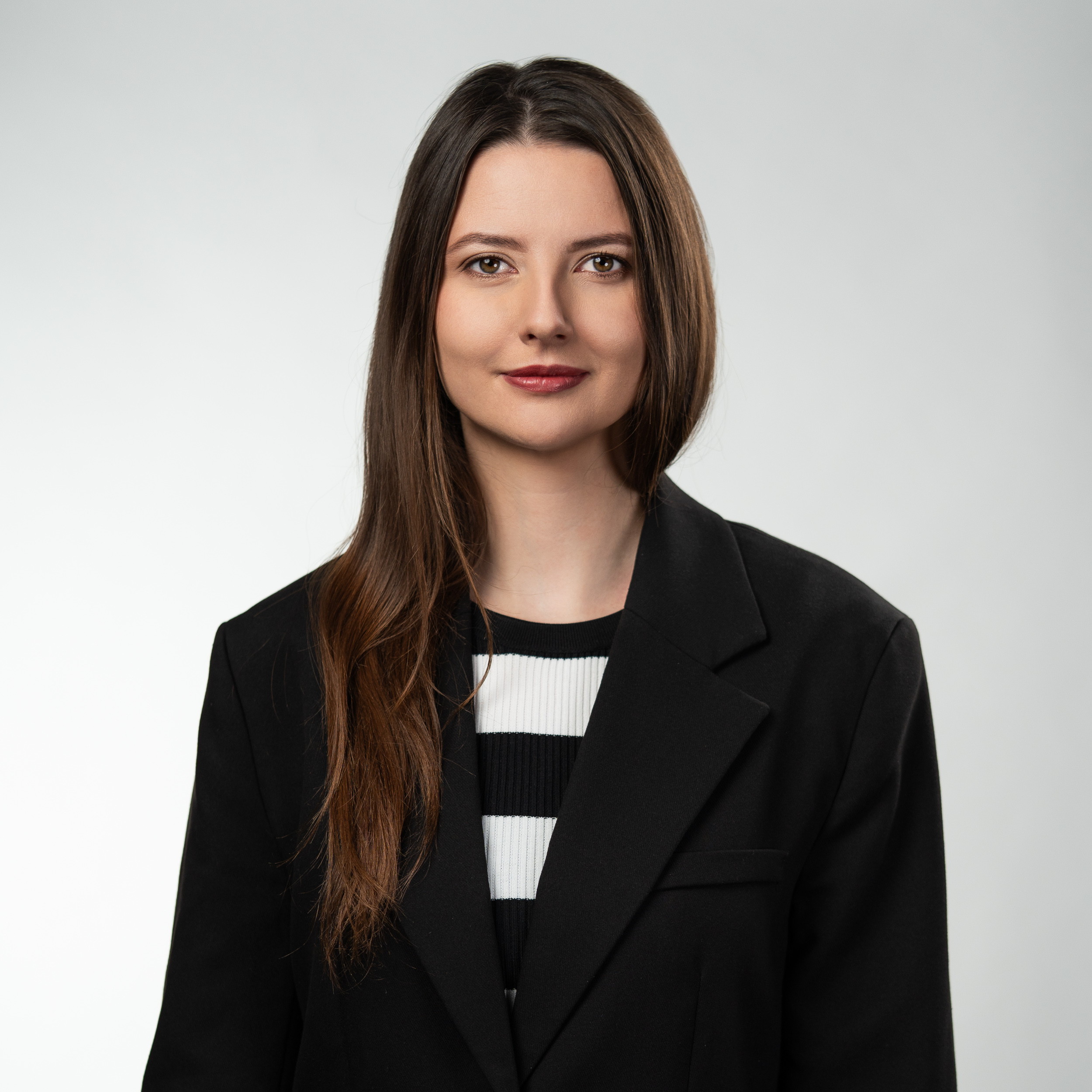 Kobieta w czarnej marynarce i pasiastym topie — headshot korporacyjny Retail Robotics